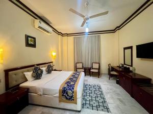 a bedroom with a bed with a ceiling fan and a desk at Farah Hotel Apartment in Muscat