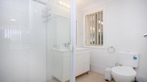 a white bathroom with a toilet and a shower at Elandra At Old Bar in Old Bar