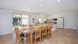 a kitchen and dining room with a wooden table and chairs at Elandra At Old Bar in Old Bar +14 photos