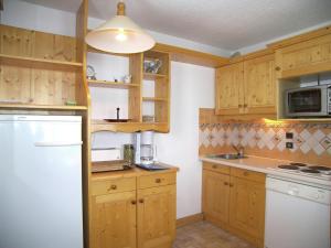 a kitchen with wooden cabinets and a white refrigerator at Spacious flat in M ribel near the ski lifts in Méribel