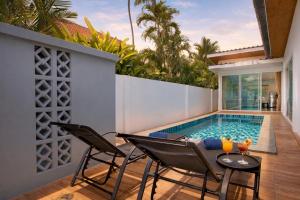 a backyard with a swimming pool and chairs and a table at 3 BR Pool Villa Lancelot in Rawai in Ban Saiyuan (1)