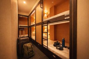 a room with bunk beds with a suitcase and a backpack at Wink at Perak Road in Singapore