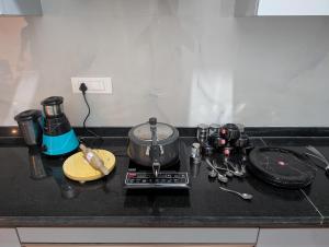 a kitchen counter with a stove with a pot and pans at Elite Homes in Chikmagalūr