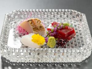 a plate of food on a table with flowers at Ishinoya Atami - TKP Hotels & Resorts in Atami