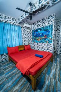 a bedroom with a red bed with a painting on the wall at Marcelo Palace - Baga in Calangute