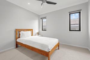 a white bedroom with a bed and two windows at Spacious 4 Bed Home with Pool & Garden in Griffin