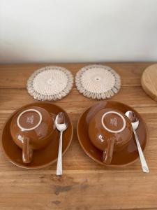 two brown plates and spoons on a wooden table at Santai Villas in Nusa Lembongan