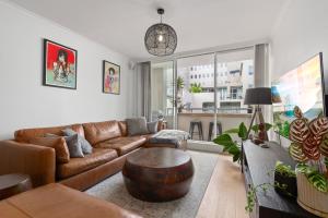 a living room with a brown leather couch and a table at Spacious 1 Bed Near Manly Beach in Sydney