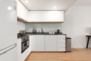 a white kitchen with white cabinets and appliances at Spacious 1 Bed Near Manly Beach in Sydney