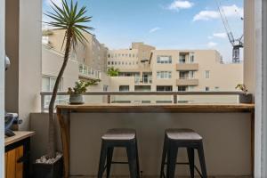 a bar with two stools and a palm tree on a balcony at Spacious 1 Bed Near Manly Beach in Sydney +6 photos