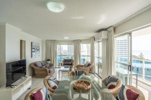 a living room with a table and chairs at Grosvenor Beachfront Apartments Surfers Paradise in Gold Coast