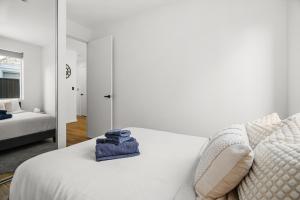 a white bedroom with a bed and a mirror at Chic Flinders Park Getaway in Adelaide