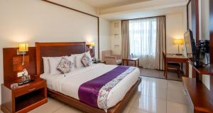 a hotel room with a large bed and a desk at Royal Orchid Central, Shimoga in Shimoga