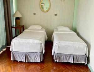 two beds in a room with white sheets and a mirror at Chom View Hotel, Hua Hin in Hua Hin +49 photos
