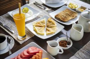 a table with plates of food and a glass of orange juice at Awan Putih Resort Ubud in Payangan