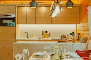 a kitchen with wooden cabinets and a table with chairs at Chalet Soleada with Fireplace and Terrace for 5 - Happy Rentals in Pian San Giacomo