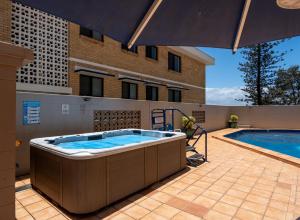 a hot tub on a patio next to a swimming pool at Grosvenor Beachfront Apartments Surfers Paradise in Gold Coast