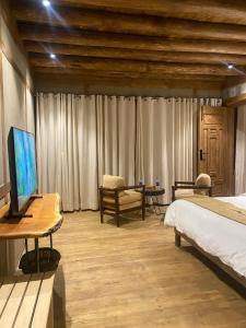 a bedroom with a bed and a desk with a television at Dera Lamsa Resort Shigar in Shigar