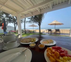 a table with plates of food on a table with the beach at Saman Beach Guest House in Galle