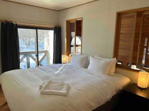 a white bed in a room with a window at Kitakaze Chalet in Myoko