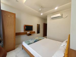 a bedroom with a bed and a tv on the wall at Hotel Avenue Gest House in Dabhoi