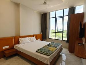 a bedroom with a bed with a large window at Hotel Avenue Gest House in Dabhoi