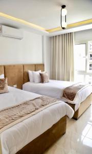 two beds in a hotel room with a window at Golden House Madinty in Madinaty
