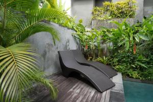 a black bench sitting on a wooden deck with plants at JAPA Suites & Villas in Ubud