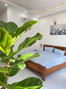 a bedroom with a bed and a large green plant at Jasmine Homestay in Danang
