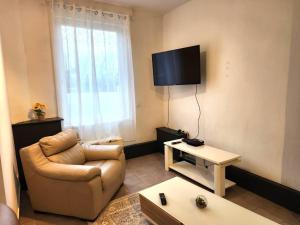 a living room with a couch and a tv on the wall at Welcome to our Mouscron cocoon in Marcinelle