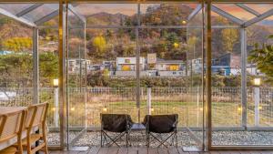 a glass house with a table and chairs in front of a window at Gapyeong Ddobagi Pet & Spa Glamping in Gapyeong