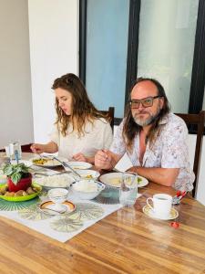 a man and a woman sitting at a table with food at Willow Nest Inn in Mahiyangana