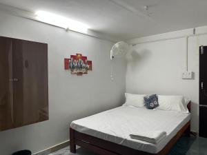 a bed in a room with a white wall at Swagatom Homestay in Jorhat