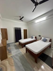 a room with two beds and a ceiling fan at Swagatom Homestay in Jorhat