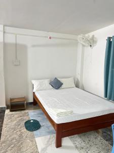 a bedroom with a bed with white sheets and a blue curtain at Swagatom Homestay in Jorhat