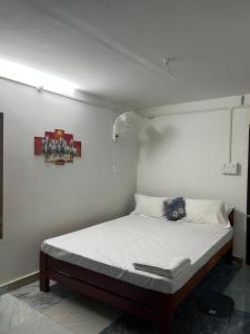 a bed in a bedroom with a white wall at Swagatom Homestay in Jorhat +14 photos