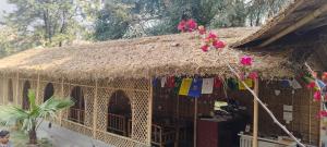 a building with a thatch roof with pink flowers on it at Pennylane Hotel - Aesthetic Rooms with pottery studio, artshala, garden cafe, free airport pickup for 7 or more nights bookings in Rishīkesh