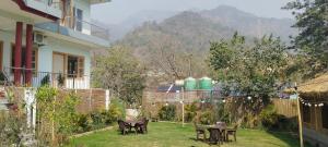 a patio with tables and chairs in a yard at Pennylane Hotel - Aesthetic Rooms with pottery studio, artshala, garden cafe, free airport pickup for 7 or more nights bookings in Rishīkesh