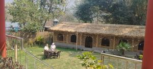 two people sitting at a table in front of a building at Pennylane Hotel - Aesthetic Rooms with pottery studio, artshala, garden cafe, free airport pickup for 7 or more nights bookings in Rishīkesh