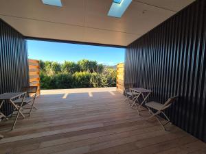 a room with tables and chairs on a deck at Accomodation at Curio in Curio Bay
