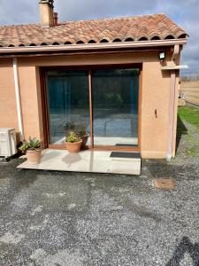 a house with a large glass door with two potted plants at Chambre paisible in Albi +2 photos