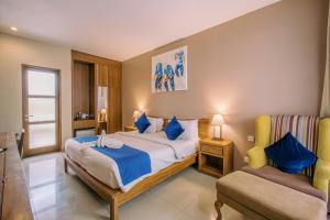 a bedroom with a large bed and a chair at Abian Harmony Hotel in Sanur