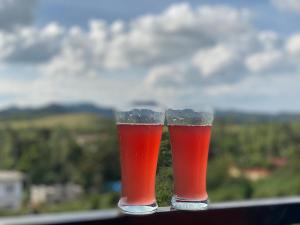 two glasses of beer sitting on top of a rail at KODAGU MOUNTAIN VIEW Rooms in Madikeri