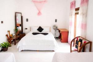 a bedroom with a white bed with a bow tie on it at Hushwood ELLA in Ella
