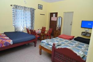 a bedroom with two beds and a table and chairs at KODAGU MOUNTAIN VIEW Rooms in Madikeri