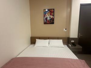 a bed in a room with a picture on the wall at Ruby Motel in Trà Phương