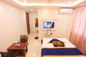 a room with a bed and a table and a tv at S V Grand Inn in Bangalore