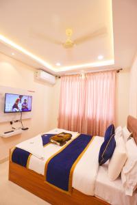 a bedroom with a large bed with a tv on the wall at S V Grand Inn in Bangalore