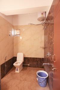 a bathroom with a toilet and a shower and a bucket at S V Grand Inn in Bangalore