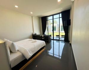 a bedroom with a bed and a desk and a window at Pearlix Koh Mook in Ko Mook